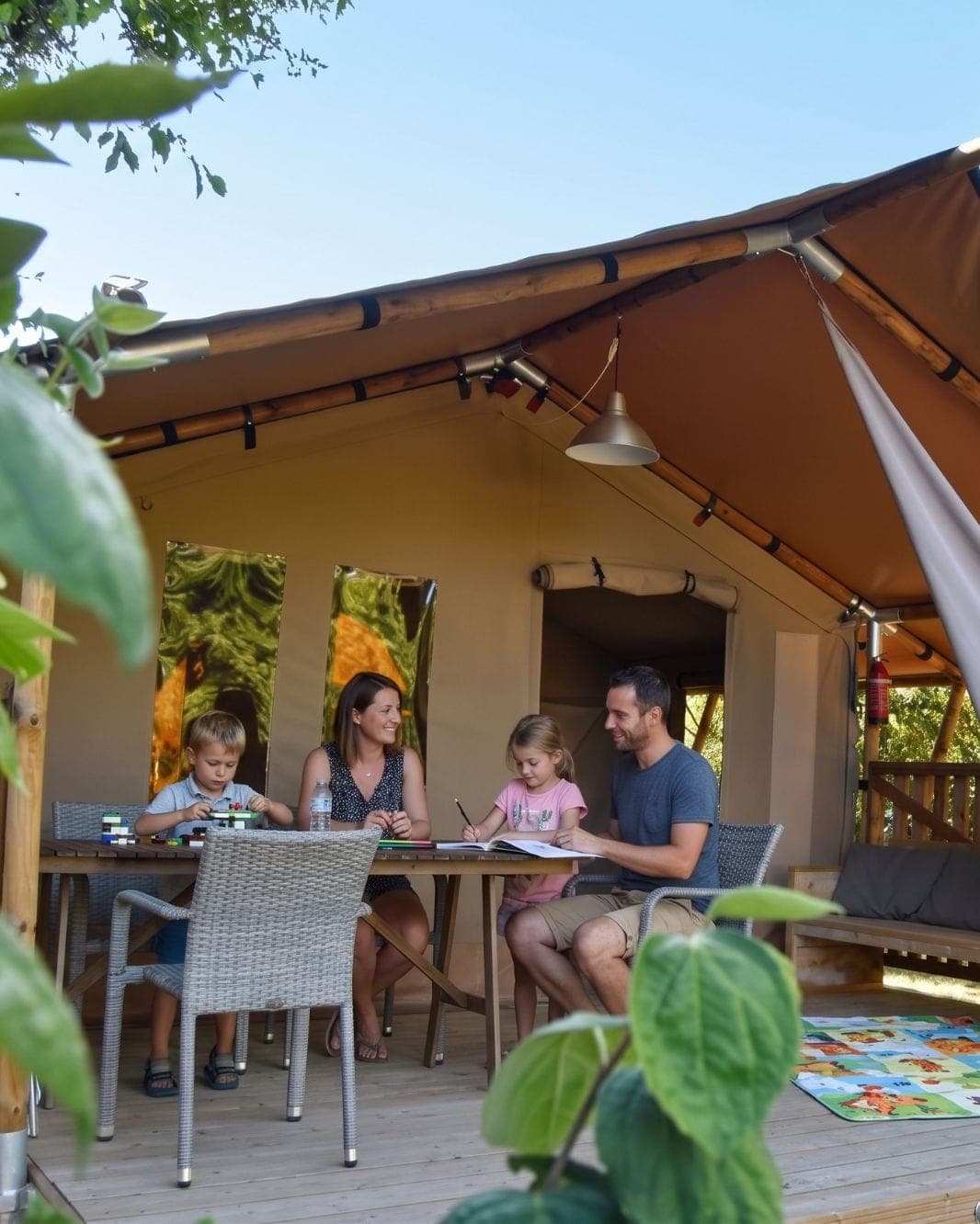 Gezin aan tafel op de veranda van een safaritent